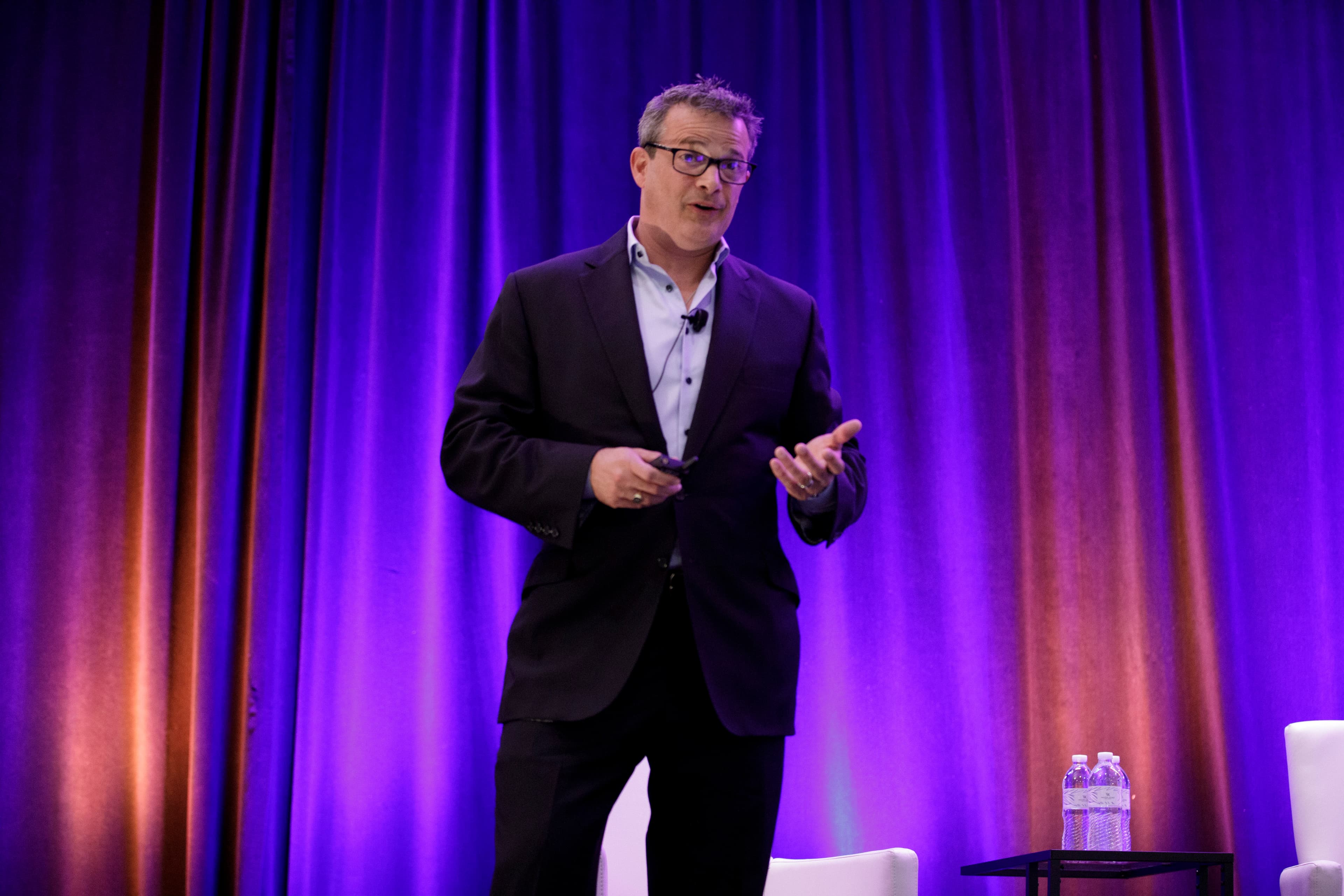 Glenn speaking on stage at a finance summit
